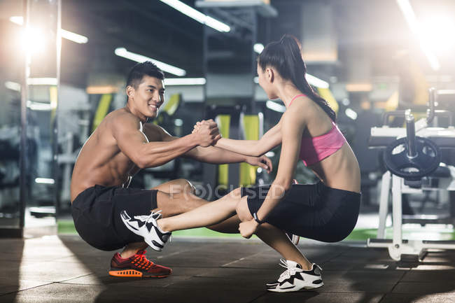 Chinese couple doing sit ups together at gym — training, wellness - Stock Photo | #178418286